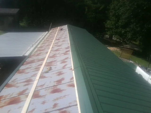 Old rusted panels beside newly installed green metal roofing — Wind Damage Roof Repair by Roofing Brothers in East Canaan