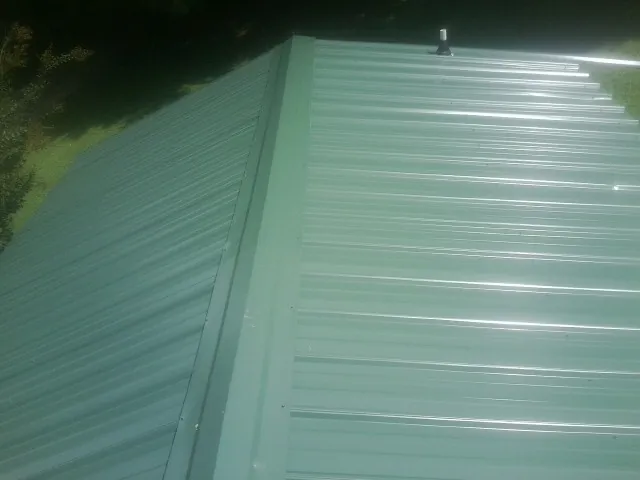New green metal panels meeting at the ridge of a roof — Flat Roof Repair work by our crew in East Canaan
