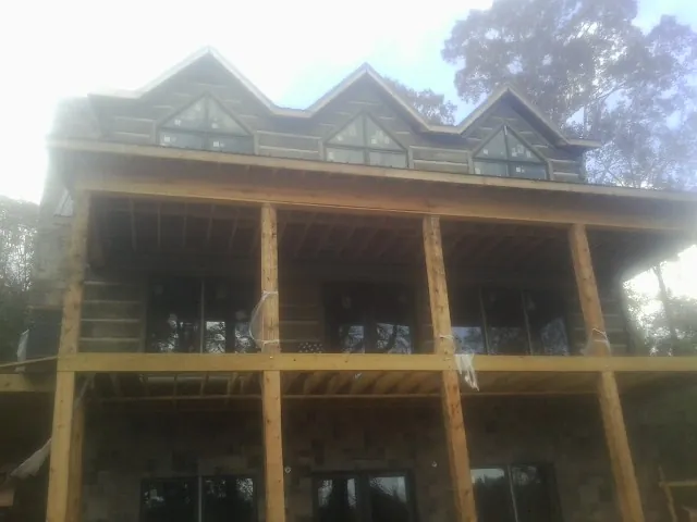 Dormers and porch framing on a large log home under construction — Roof Coating work by our crew in East Canaan