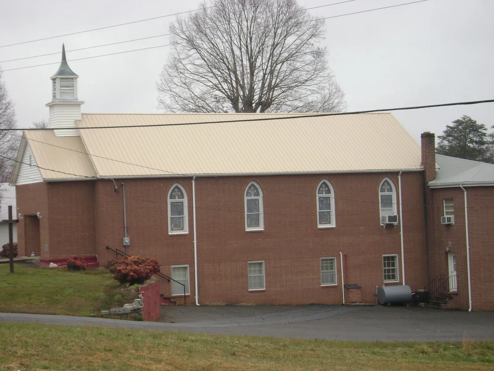 New tan metal roof on a brick church with a white steeple in East Canaan