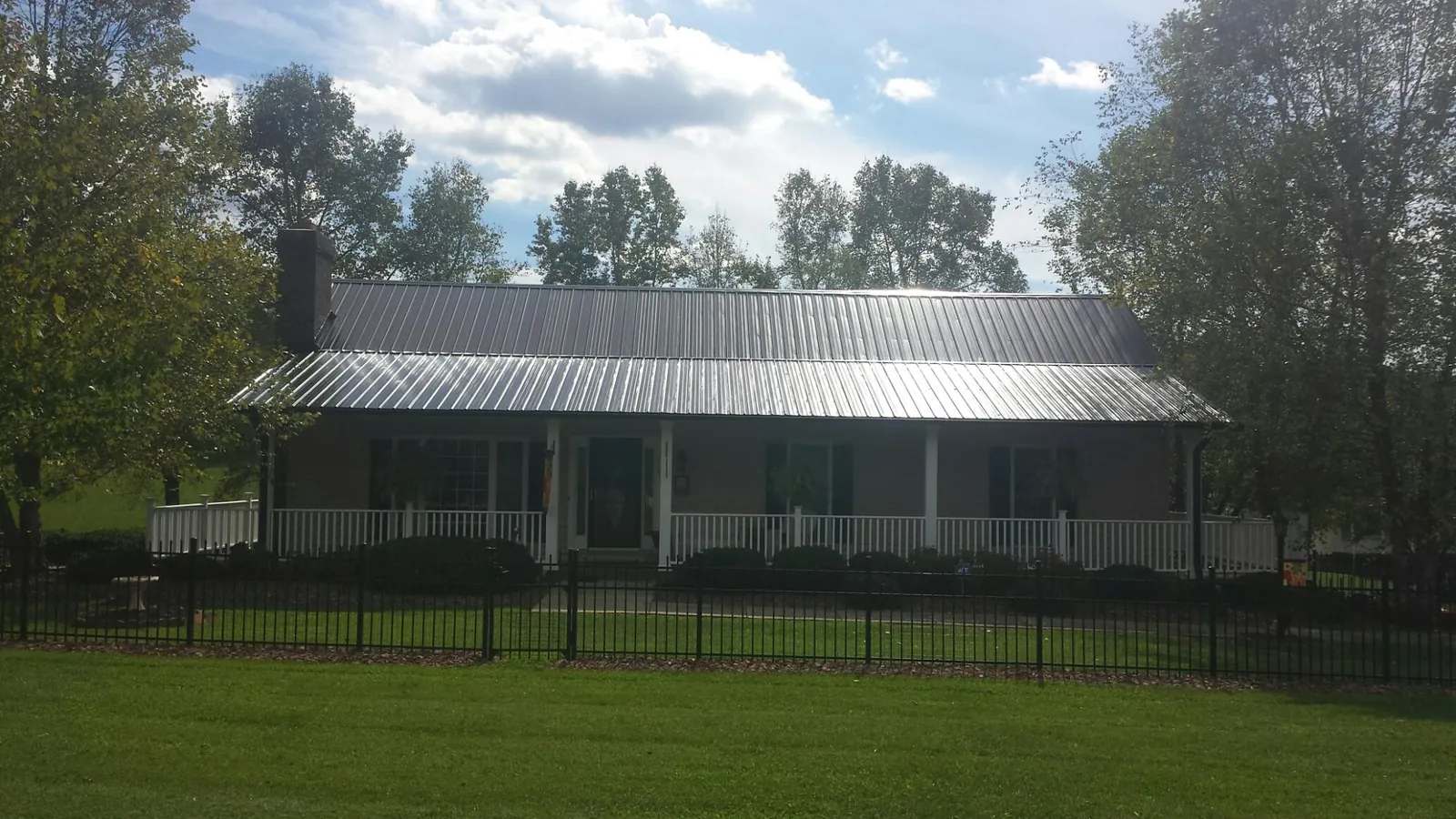 Gray metal roof on a brick ranch with a full width front porch — Gutter Guard Installation work by our crew in East Canaan