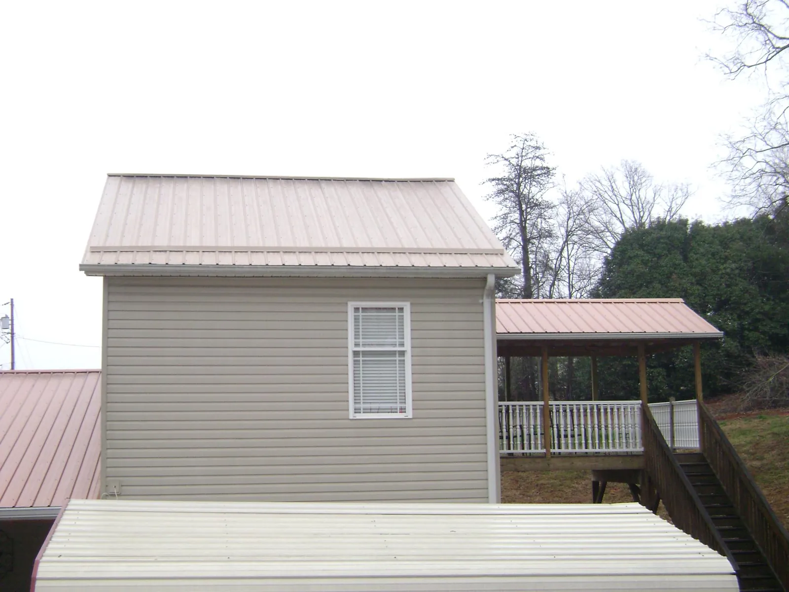 Tan metal roofs on a two story addition and attached porch, from a Roof Replacement job in East Canaan