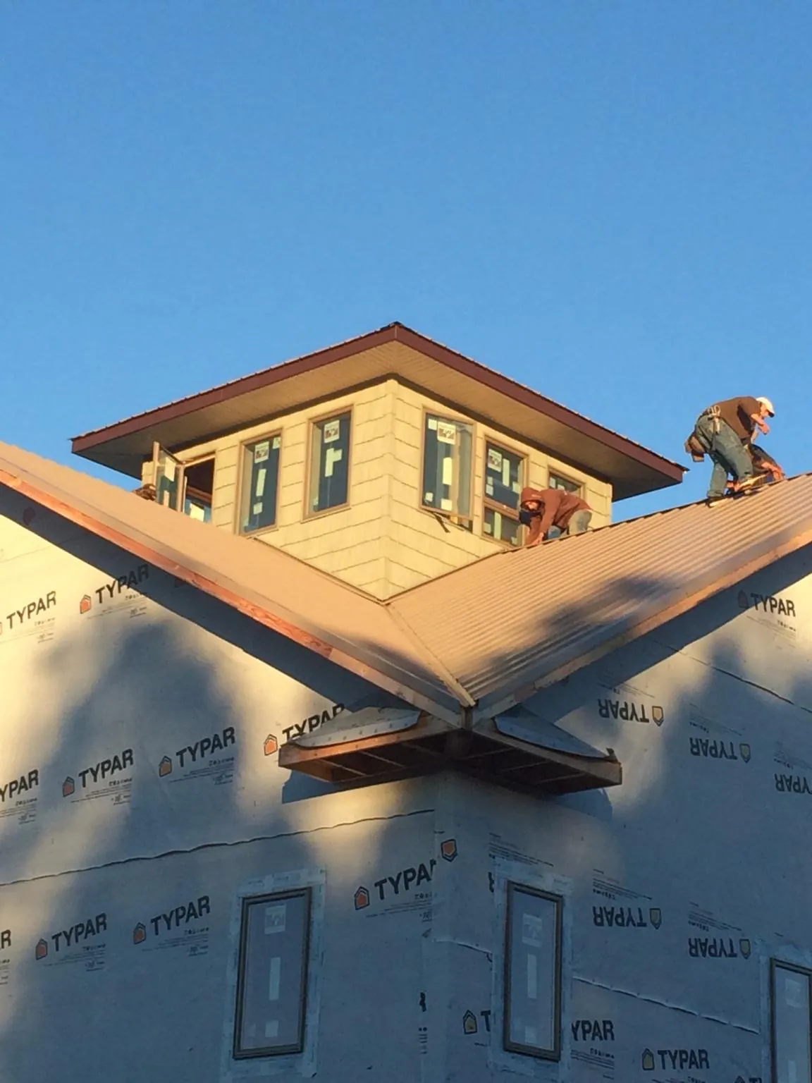Roofers working around a rooftop cupola on a new metal roof at sunset — Roof Waterproofing in East Canaan by Roofing Brothers